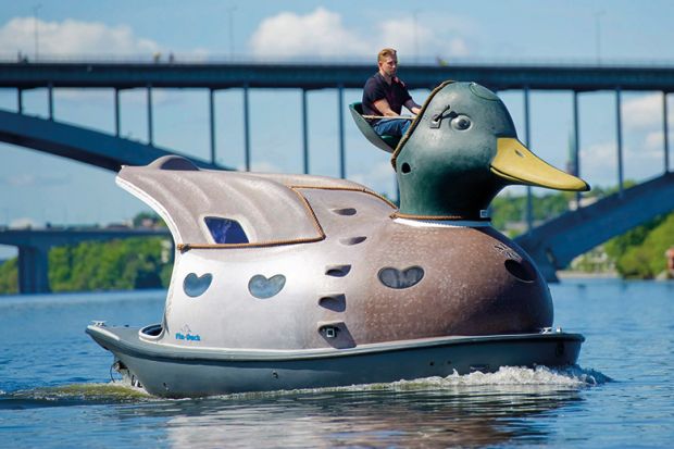 man driving giant duck on river