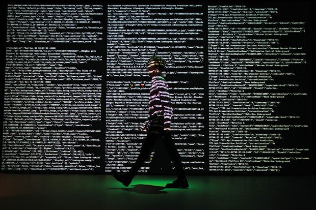 man walking past screen of code at Big Bang Data exhibition