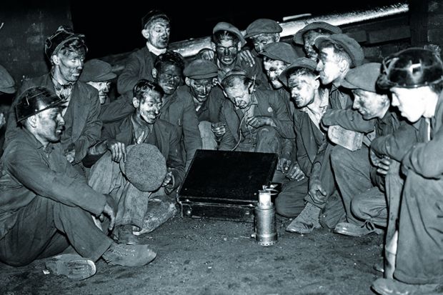 Coal miners sitting around radio in briefcase