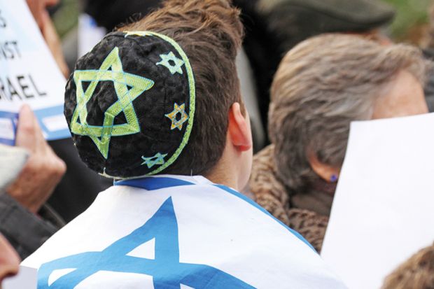 A Israeli youth with a flag draped around his back. Star of David, Jewish.