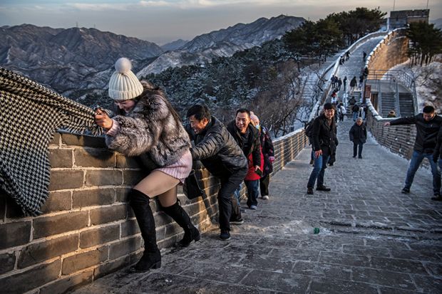 A Chinese tourist uses the scarf of a friend as she is helped while she and others  struggle to climb in the wind on an icy section of the Great Wall at Badaling, on a cold day after a snowfall