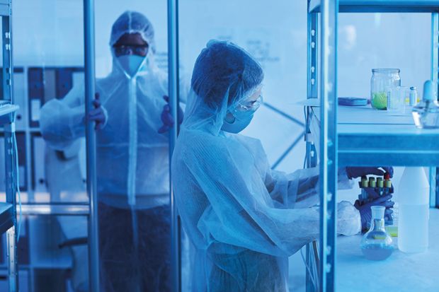 male medical scientist in protective workwear opening door to laboratory room