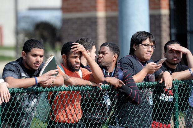 Students line the fence at the football field at university, USA 