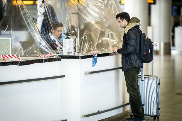 A passenger stands at an airline counter protected with a plastic tarpaulin on March 27, 2020, Netherlands