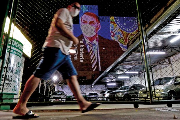 An image of Brazil's President Jair Bolsonaro wearing a protective face mask and the phrase Hysteria Damages the Economy is projected on the wall of a building as a protest against the president regarding his handling of the coronavirus COVID-19 outbreak