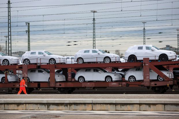 New Audi AG automobiles, manufactured by Volkswagen AG, sit under protective covers on a railway transporter beside a platform at Ingolstadt central train station in Ingolstadt, Germany