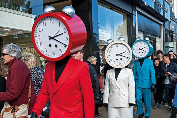 Three people dressed in red, white and blue suits with clocks for heads