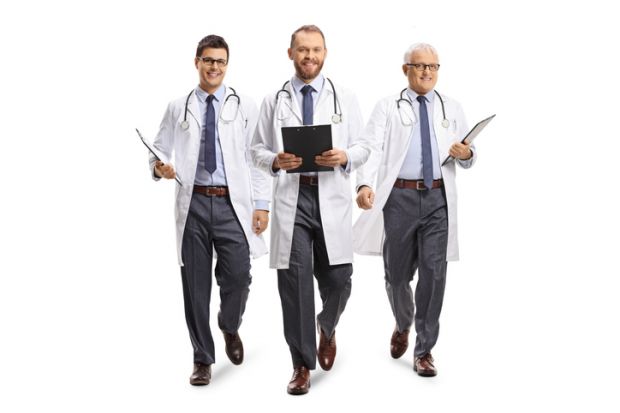 Three male doctors smiling and walking towards camera