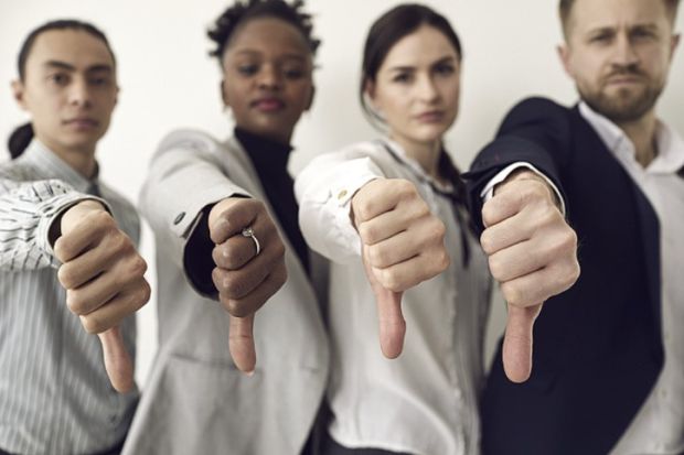 Four people giving a thumbs-down signal