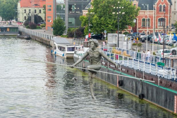 Statue of a tightrope walker crossing a Polish river