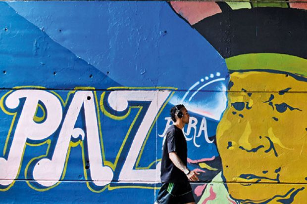 Man walking past paz graffiti in Colombia
