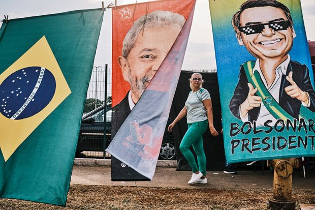 A woman walks by flags of Brazilian presidential candidates Luiz Inácio Lula da Silva and Jair Bolsonaro