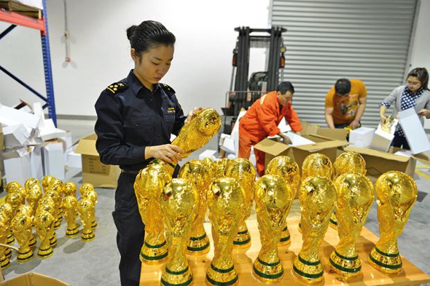 A woman standing over a box of football trophies