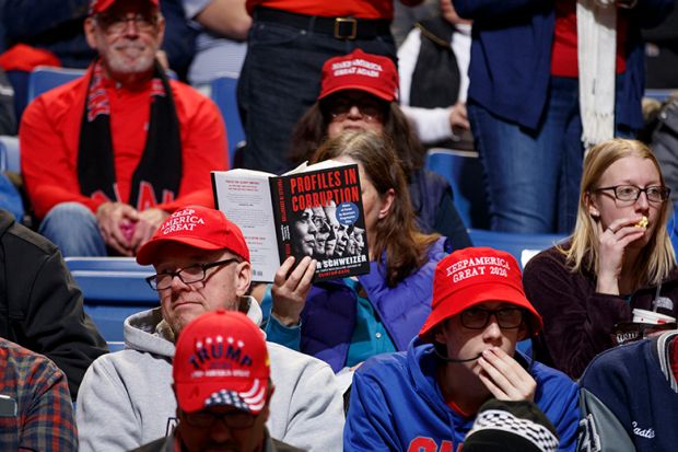 A rally attendee reads a book titled 'Profiles In Corruption', featuring 2020 Democratic presidential candidates ahead of a campaign rally for President Donald Trump. To illustrate that academic publishers are braced for a slowdown from Trump's DEI purge. A rally attendee reads a book titled 'Profiles In Corruption', featuring 2020 Democratic presidential candidates ahead of a campaign rally for President Donald Trump. To illustrate that academic publishers are braced for a slowdown from Trump's DEI purge.