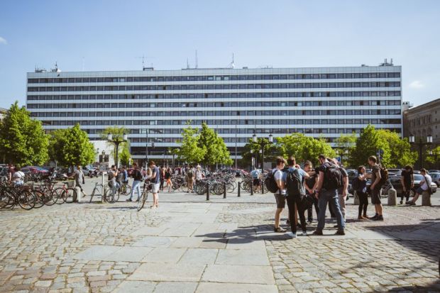 A large rectangular building with several students and bikes near it 