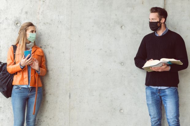 Two students standing in social distance wearing face mask