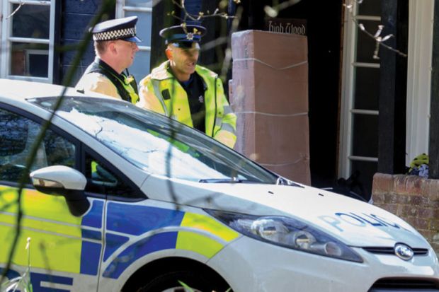 United Kingdom policemen standing by patrol car