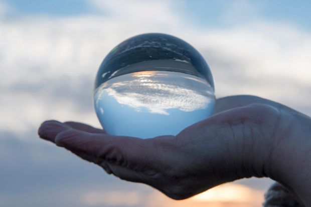 Hand holding a glass globe with a reflection of a sunset
