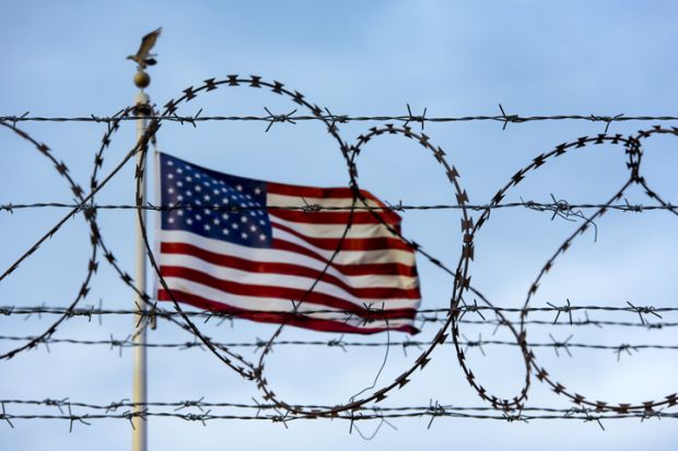 US flag behind barbed wire symbolising restrictions on international students coming to the US