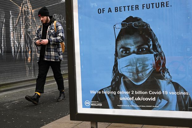 A pedestrian walks past a Unicef poster promoting Covid-19 vaccines, in Manchester, January 5, 2021, illustrating vaccine passports for campuses