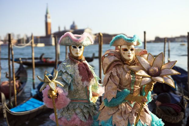Venice, Veneto, Italy - February 19, 2020 Colourful and beautifully crafted costumes for this couple posing at San Marco square waterfront at sunset.