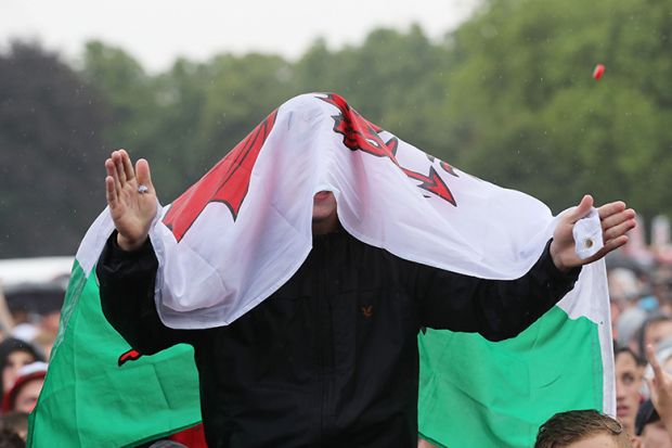A Wales fan in the rain with flag covering his head. To illustrate that changes to student finance pledged by the front runners in the upcoming Welsh election may be unworkable. A Wales fan in the rain with flag covering his head. To illustrate that changes to student finance pledged by the front runners in the upcoming Welsh election may be unworkable.
