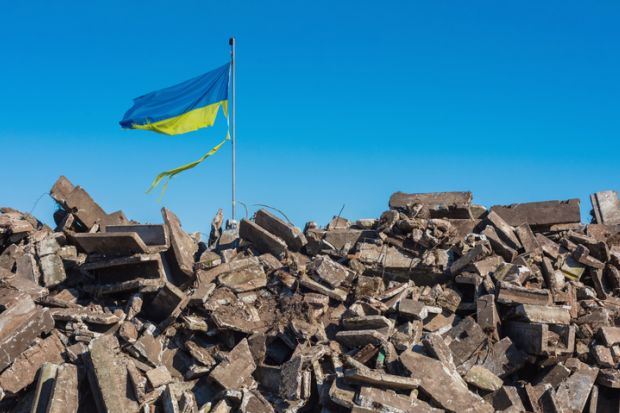 War in ukraine. Destroyed Ukrainian building and damaged flag in the wind