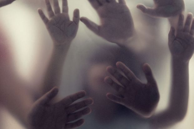 Many hands in silhouette pressed against frosted glass as a metaphor for Academic freedom can mean acknowledging trauma