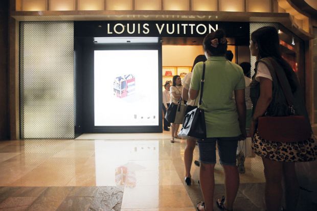 Customers wait in line outside a Louis Vuitton store n Seoul, South Korea, to illustrate High costs fail to dim Seoul’s allure to Korean students