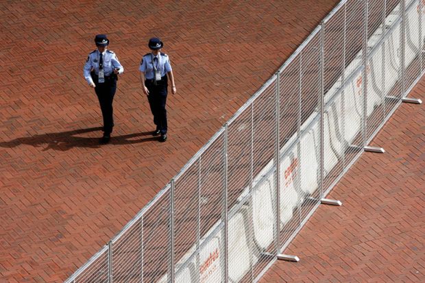 Two police officers walk alongside a steel and concrete fence erected around the Sydney Convention and Exhibition centre at Darling Harbour in Sydney to illustrate Sharing ban bill could mean jail for researchers