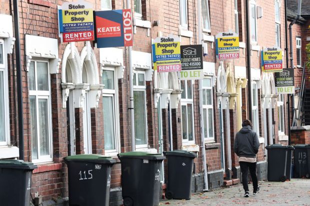 A man walks past a street of terraced houses advertising properties to illustrate Average student rents now eat up all of maintenance loan – survey