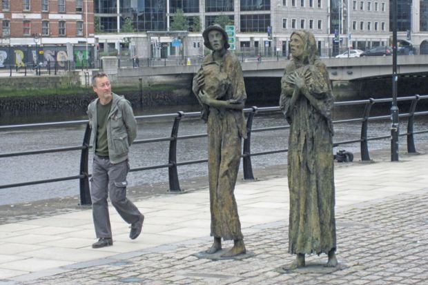 Man walking past the famine remembrance statues in Dublin