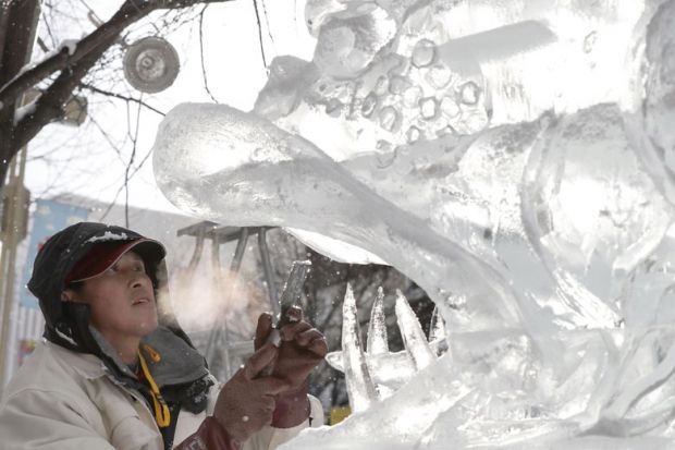  Ice Sculpture with his hands inside the mouth of a lion sculpture in Japan to illustrate Japan tries tax breaks to get companies to hire more PhD student