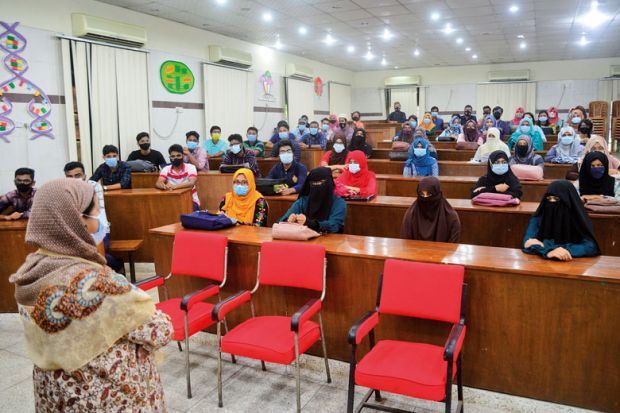 Dhaka University students wearing face masks attend their class 
