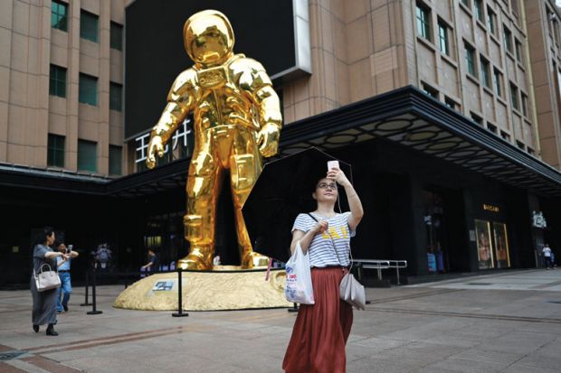 Person taking selfie with an astronaut-installation as a metaphor for  Prioritise women for research funding, Chinese universities told