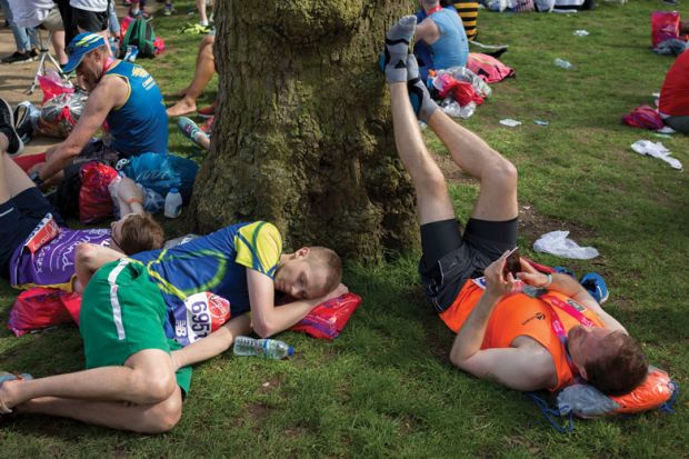 Tired long-distance runners rest after finishing the London Marathon to illustrate people are deep tired