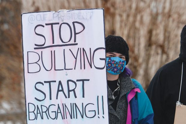 Protester holding banner while on strike over wage and workload disagreements in Edmonton, Alberta, Canada to illustrate Canadian campuses battle labour unrest and political meddling
