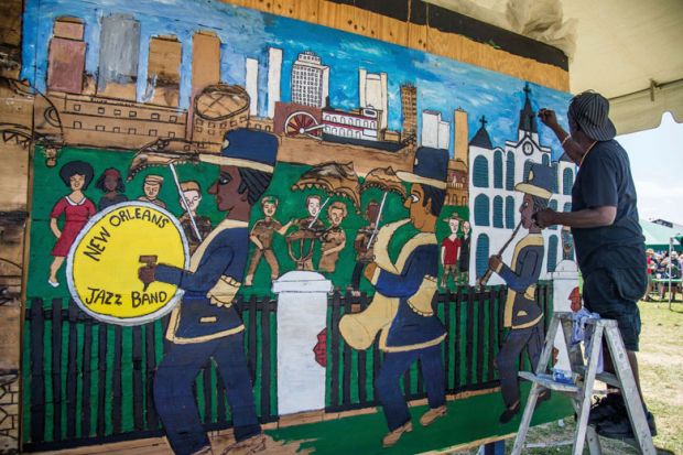 Artist painting a mural of the New Orleans Jazz and Heritage Festival to illustrate Tulane institute aims to help New Orleans ‘resurrect jobs pipeline’