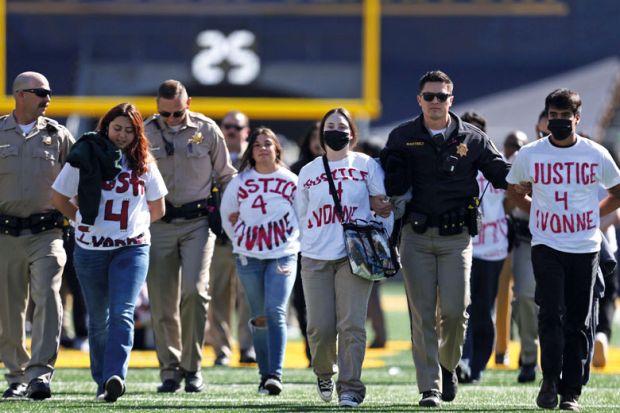  Protestors are escorted off the field by police after preventing the start of the Southern California vs. California NCAA college football game to illustrate Craving for truth in del Valle protests