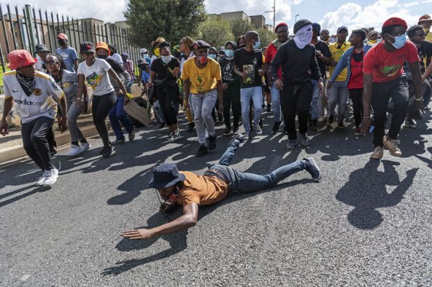  Student on the ground at a protest over university fees in Johannesburg, South Africa to illustrate Are South African  universities falling?
