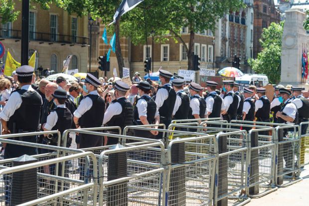  Police standing along a line barriers outside Downing Street as a metaphor for  a Peer sniffs ‘real chance’ of success on UK contract cheating law