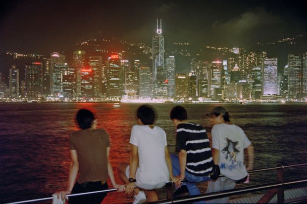 Four people enjoying a night view of the famous Victoria Harbour to illustrate Chinese school-leavers look closer to home for international study