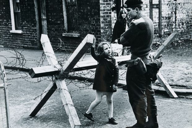 A young girl talking to a British soldier manning a roadblock on a street in Belfast, Northern Ireland during The Troubles, summer 1973