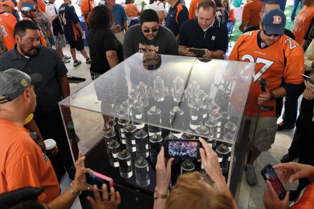 Football fans take a peek at Super Bowl rings in a glass display case to illustrate they are looking at  a 'small piece of excellence' which resembles the university as the university teaches in a research base approach producing high qualit