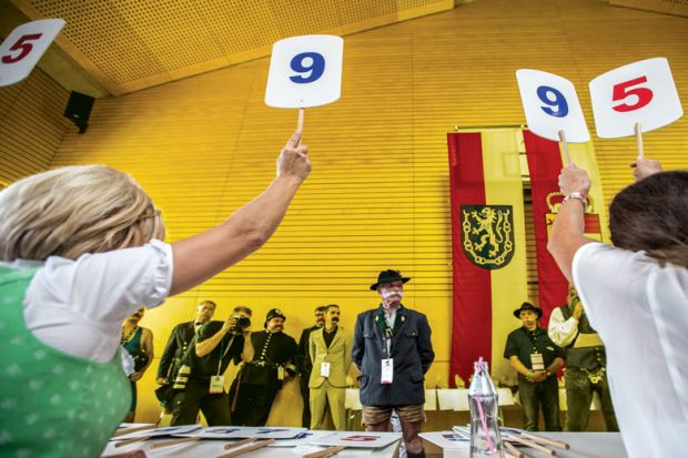 Contestants line up for judging panel who are holding up scores on boards as a metaphor for Discretion’ has no place in determining degree classifications