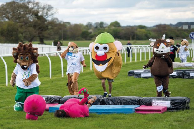 Runners dressed as mascots with a  dinosaur fallen in front to illustrate 
