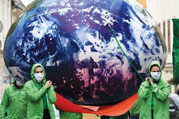 People carry giant balloon of planet Earth as a metaphor to the climate crisis is undeniably a global challenge