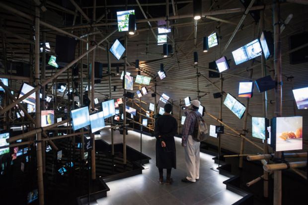 Exhibition hall with irregular arrangement of multimedia screens in Milan to illustrate Major universities play catch-up as Italian students move online