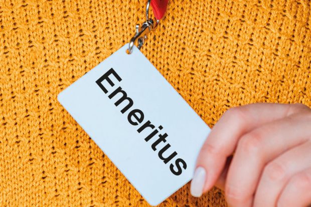 Close up of a hand holding badge name tag reading 'Emeritus' to illustrate Why I am not going to call myself a ‘professor emerita’