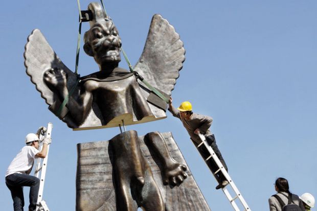 Workmen install a 6-metre fibre glass statue of the god Pazuzu onto the rooftop of the Institute of the Contemporary Arts to illustrate Science degrees ‘unwelcoming’ to religious students
